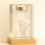 Stiklinė žvakidė su degančia arbatine žvake šalia kristalinio bloko